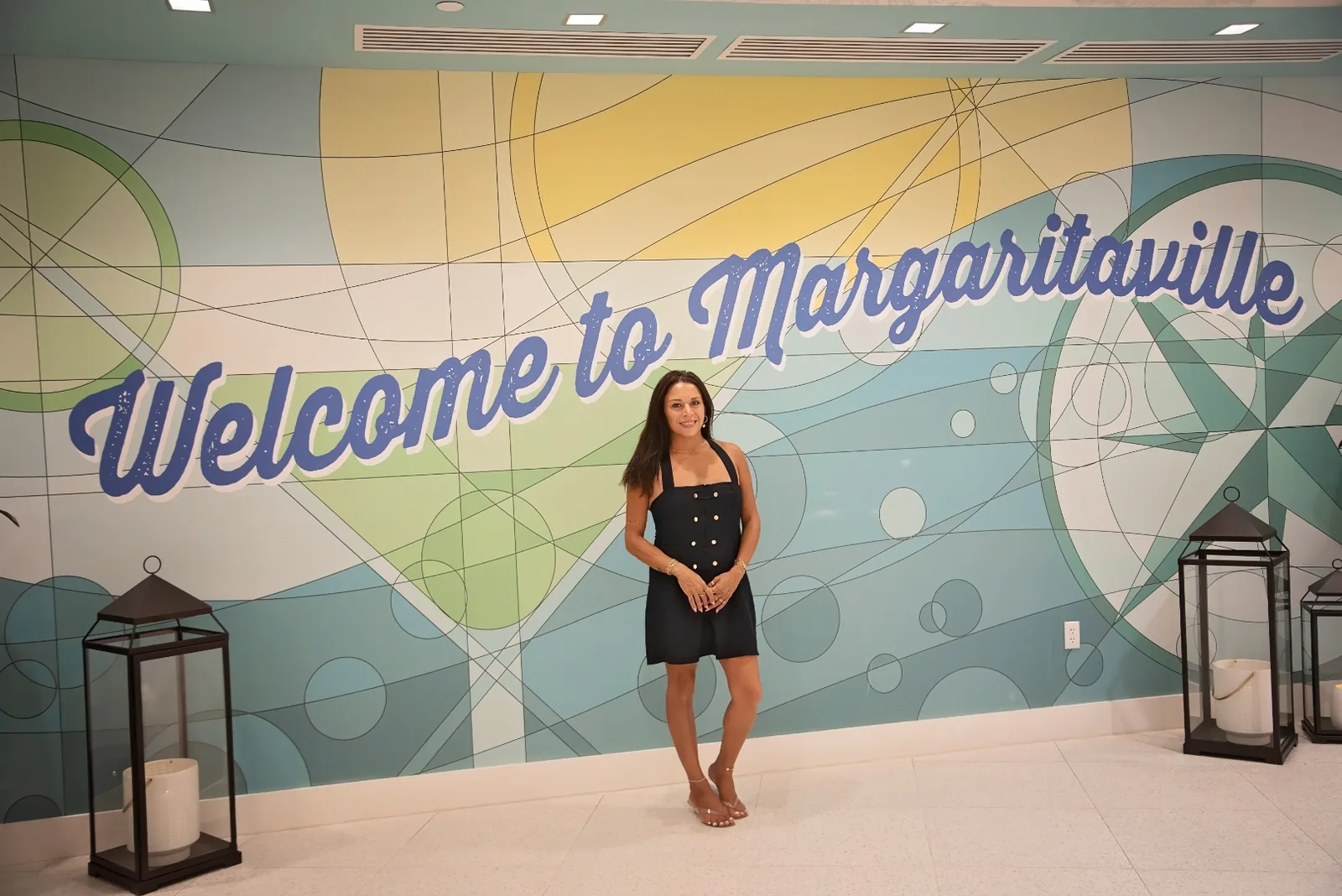 Emmy Paola Akin, founder of I Shine Permanent Jewelry, in front of the Welcome to Margaritaville mural
