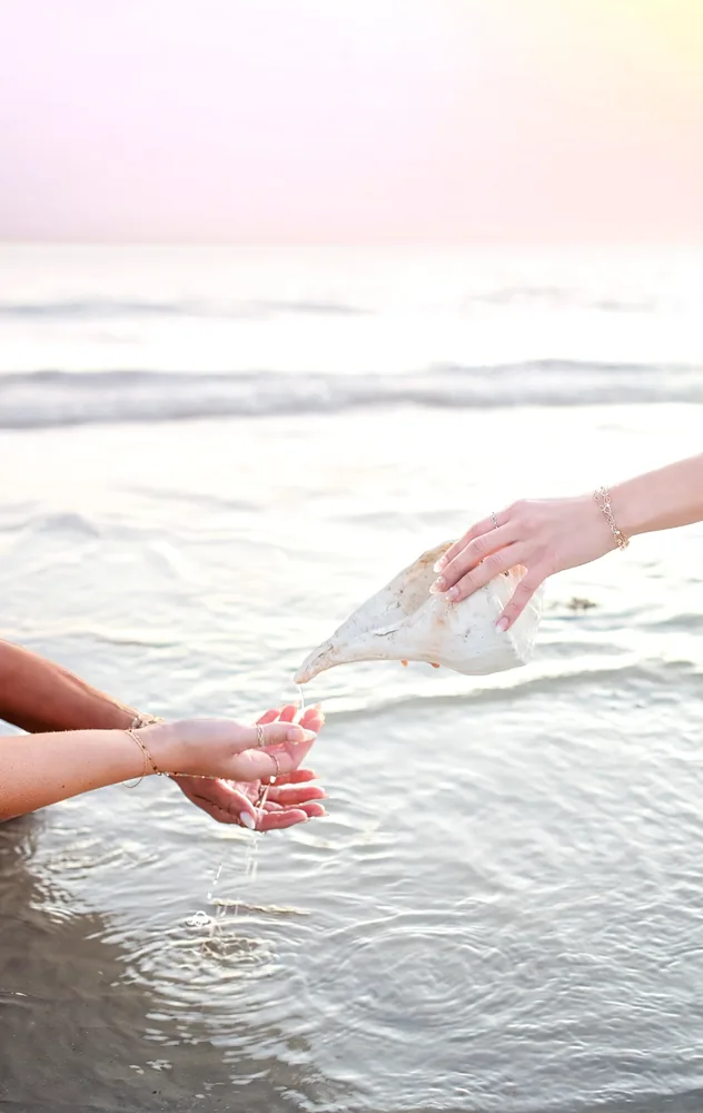 Hands decorated with thin gold permanent bracelets and rings