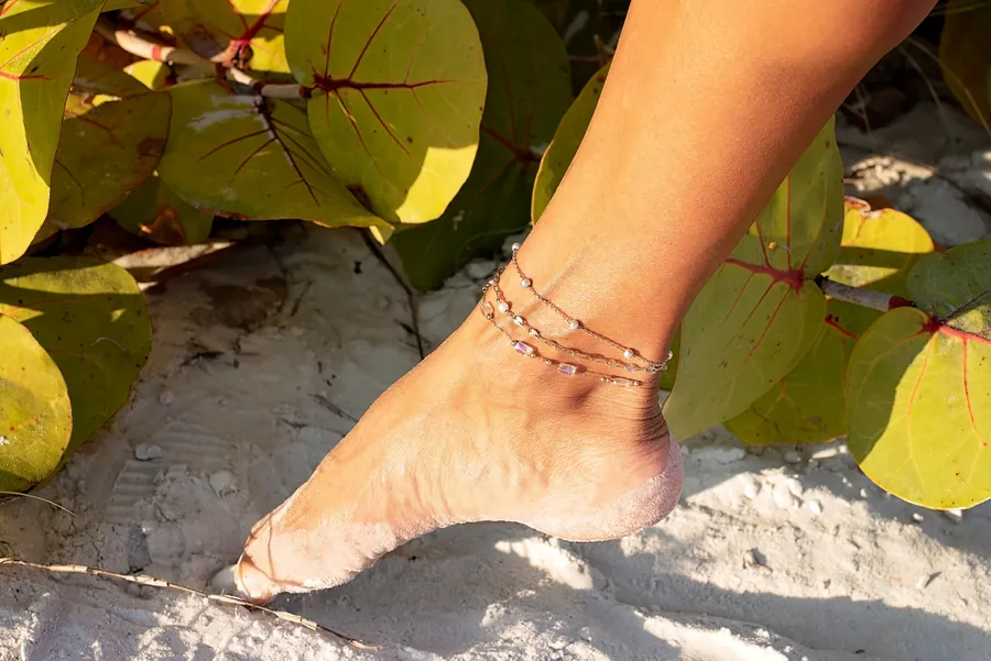 Triple-strand gold permanent anklet with pearls on the beach