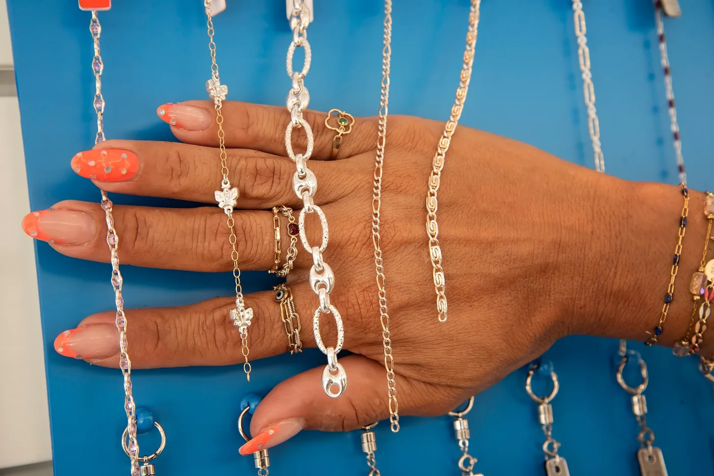 Sterling silver mariner, figaro and rope chains laid across a hand to compare widths