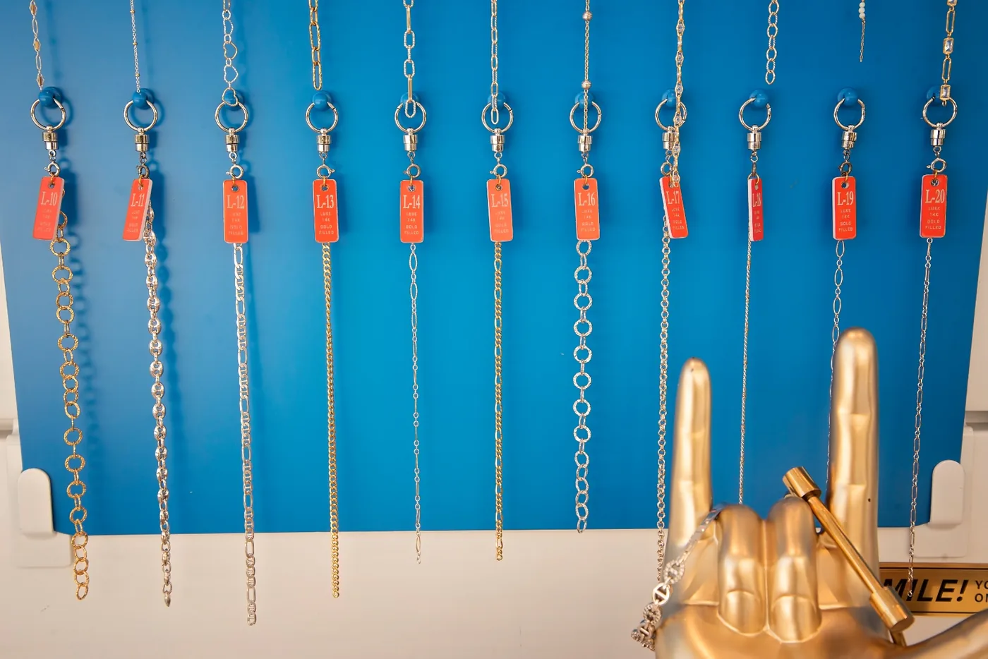 A row of numbered gold-filled chain samples hanging above the I Shine kiosk counter
