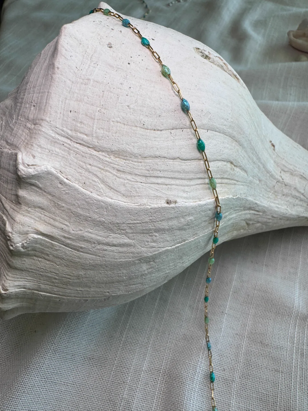 Turquoise-and-green beaded permanent chain over a smooth conch shell
