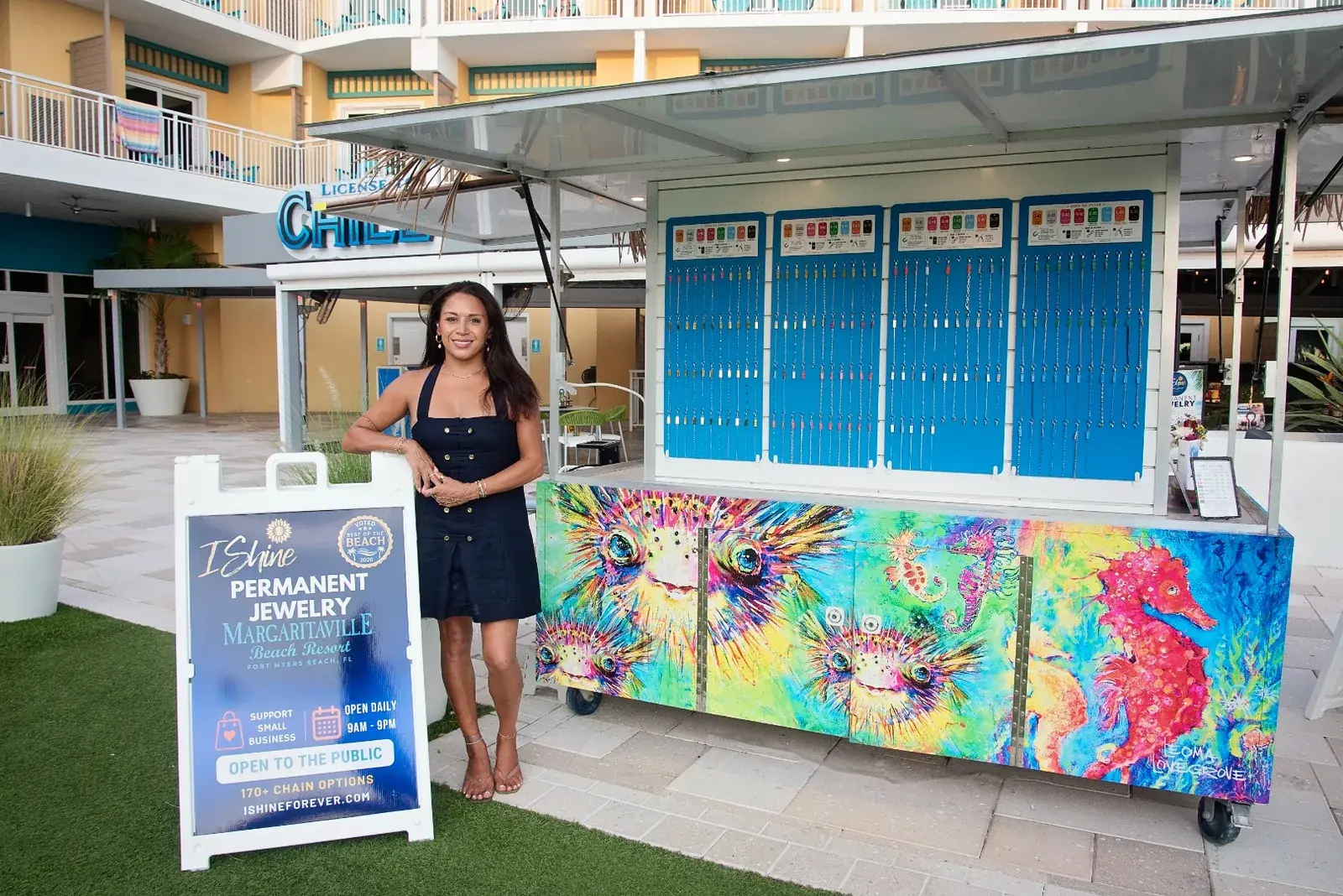 The I Shine Permanent Jewelry kiosk with its tiki roof, painted seahorse counter and sidewalk sign on the Sunset Terrace at Margaritaville Beach Resort Fort Myers Beach